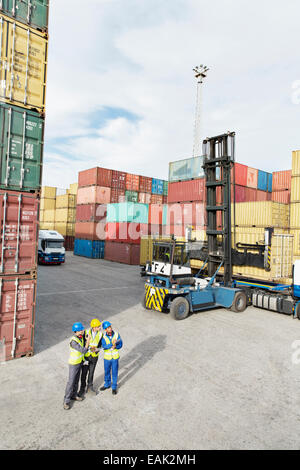 Businessmen and worker talking near cargo containers Stock Photo