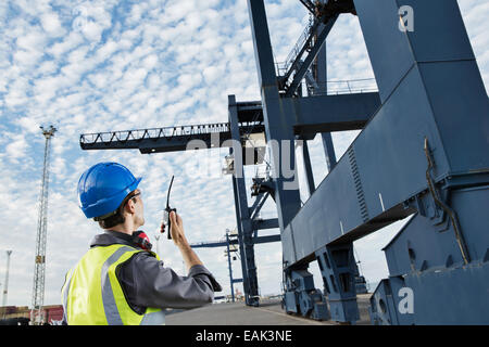 Worker using walkie-talkie under cargo crane Stock Photo