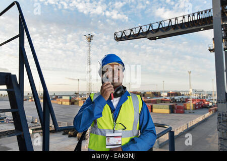 Worker using walkie-talkie on cargo crane Stock Photo