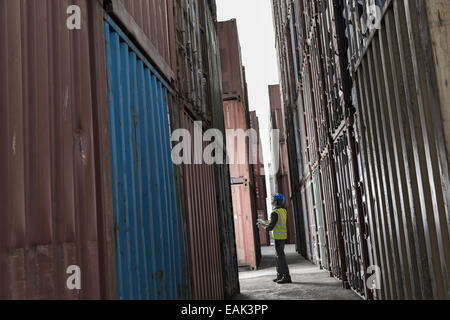 Worker standing between cargo containers Stock Photo