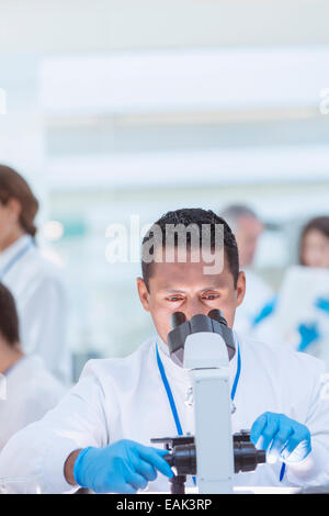 Scientist examining sample under microscope in laboratory Stock Photo