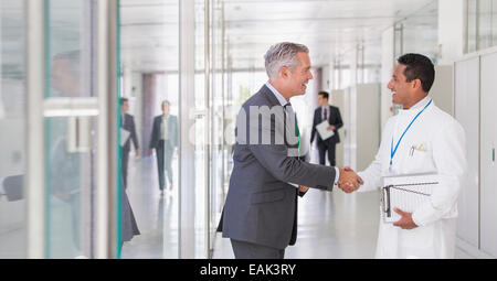 Scientist and businessman shaking hands in hallway Stock Photo