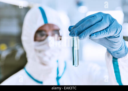 Close up of scientist in clean suit examining sample in test tube Stock Photo