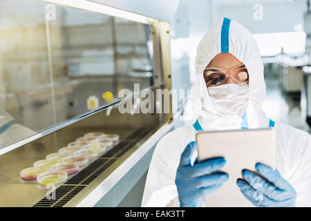 Scientist in clean suit using digital tablet in laboratory Stock Photo