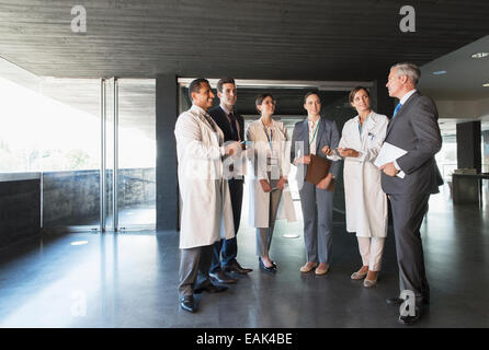 Scientists and business people talking in lobby Stock Photo