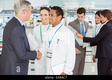 Scientist and businessman shaking hands in laboratory Stock Photo