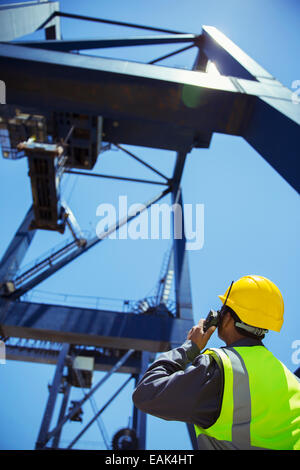 Low angle view of worker using walkie-talkie near crane Stock Photo
