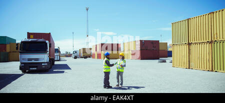 Workers talking near cargo containers Stock Photo