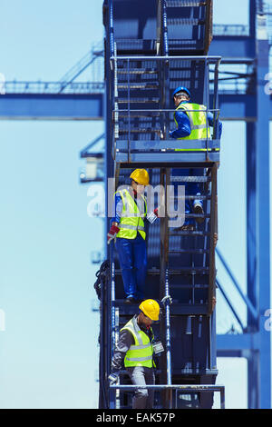 Businessman and workers climbing stairs on cargo crane Stock Photo