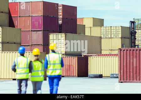 Workers and businessman walking near cargo containers Stock Photo