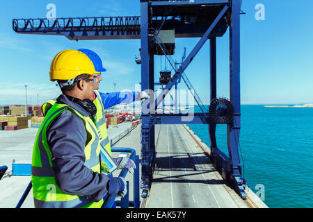 Worker and businessman examining cargo crane at waterfront Stock Photo