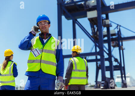 Worker using walkie-talkie near cargo crane Stock Photo