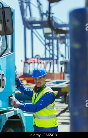 Worker climbing into truck near cargo crane Stock Photo