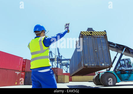 Worker directing crane carrying cargo container Stock Photo