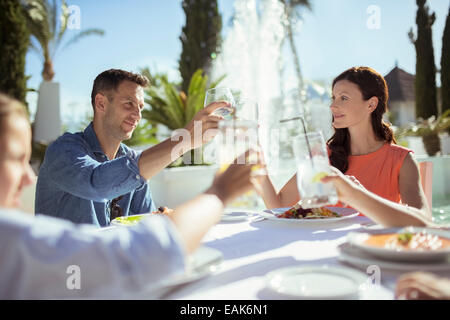 Family raising toast at table outdoors Stock Photo