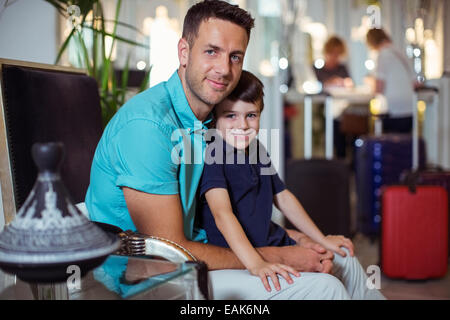 Portrait of man with son sitting in hotel lobby Stock Photo