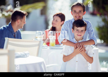 Portrait of smiling brother and sister, parents sitting at table in background Stock Photo