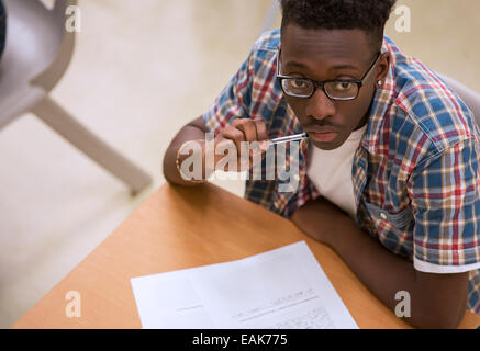 Portrait of male student wearing glasses sitting at desk in classroom Stock Photo