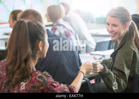 Smiling female students exchanging notes in classroom Stock Photo