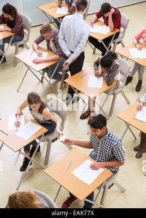 Overhead view of students passing note between desks during their GCSE exam Stock Photo