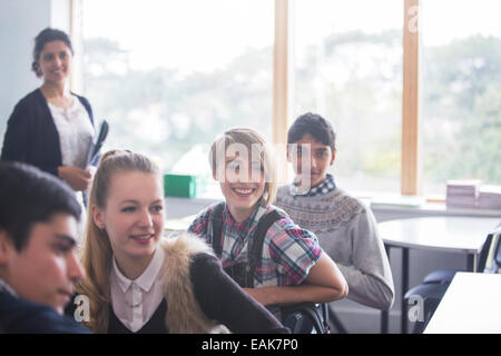 Cheerful high school students with their teacher in classroom Stock Photo
