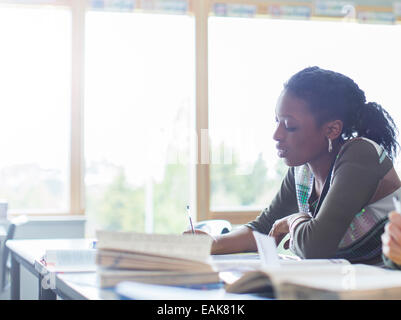 Female student writing at desk in classroom Stock Photo