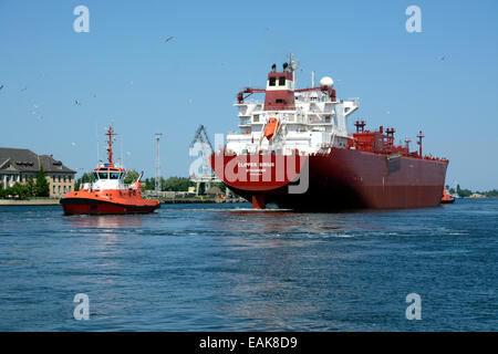 A cargo ship is towed from the Gdansk shipyard by a tug boat, Gdansk, Pomeranian Voivodeship, Poland Stock Photo