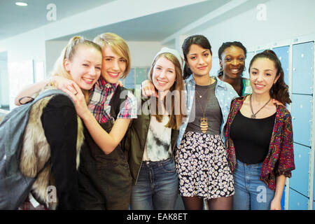 Group portrait of cheerful female students standing in locker room Stock Photo