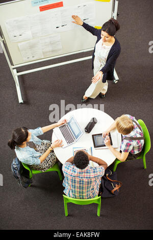 Overhead view of student looking at teacher showing documents on whiteboard Stock Photo