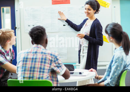 Student looking at teacher showing documents on whiteboard Stock Photo