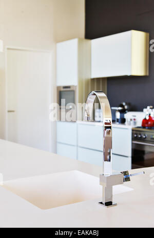 Modern stainless steel faucet and white kitchen sink in clean kitchen
