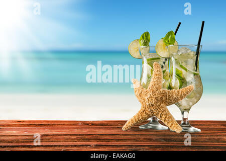 Exotic summer drinks served on wood. Blur sandy beach as background Stock Photo