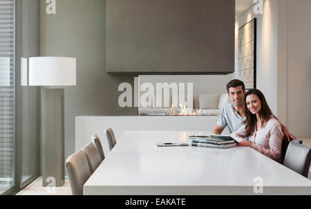 Portrait of happy couple sitting in dining room with books and digital tablet on table Stock Photo