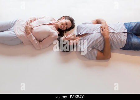 Couple looking at each other while lying on table Stock Photo