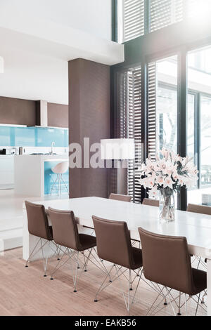 View of modern dining room with white lilies in vase on table Stock Photo