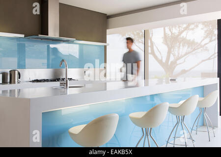 Blurred motion man walking through white and blue modern kitchen Stock Photo