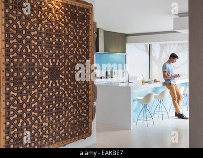 Man leaning against kitchen counter and texting Stock Photo