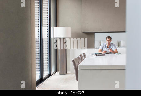 Man sitting at table and texting in dining room Stock Photo