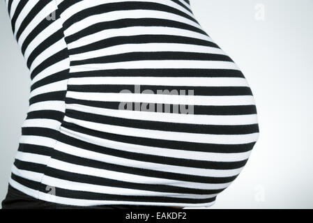 Close up of pregnant woman belly wearing black striped top Stock Photo