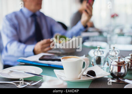 Close up of coffee cup on restaurant table, man in background