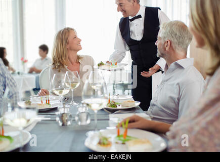 Waiter serving fancy dish to woman sitting at restaurant table Stock Photo