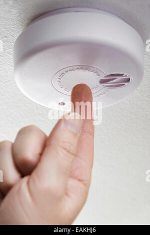 Close Up Of Hand Testing Domestic Smoke Alarm Stock Photo