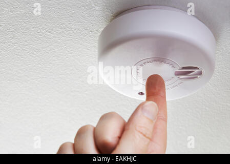 Close Up Of Hand Testing Domestic Smoke Alarm Stock Photo