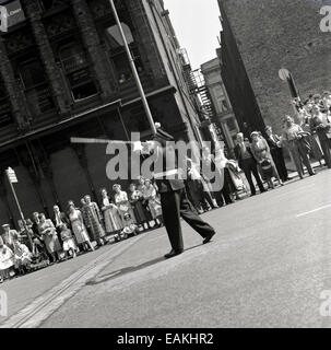 1950s, historical, people watch by the roadside in Manchester city centre as a band marches in the traditional Whitsun parade to celebrate the birthday of the Christian church. Such processions date back to 1784 and the birth of the Sunday school movement. Stock Photo