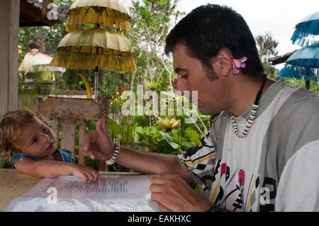 Afather with his daughter checking food menu at a restaurant in Ubud. Indonesia. Ubud offers a wide choice of restaurants, from Stock Photo