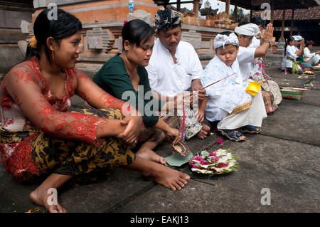 A BALINESE family prays at PURA TIRTA EMPUL a Hindu Temple complex and cold springs - TAMPAKSIRING, BALI, INDONESIA. Several peo Stock Photo