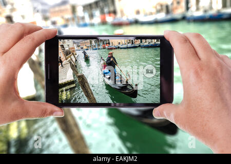 a mobile phone snapping a picture of a gondolier on his gondola in venice Stock Photo