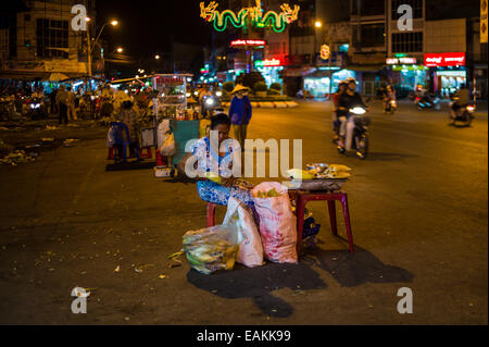 Woman vendor selling grilled corn at the night market in the streets of Tra Vinh, Vietnam. Stock Photo