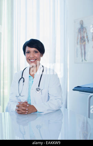 Portrait of smiling female doctor sitting at desk in office Stock Photo