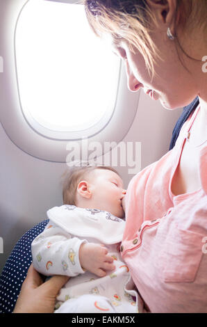 Mother breastfeeding a two month old baby girl on an aeroplane Stock Photo
